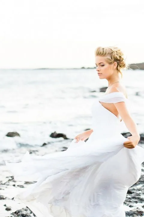 A beautiful wedding photograph of a bride on a cliff edge against a sunrise.